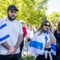 Two students stand together, one carrying a blue and white Israeli flag, the other student wearing a large Israeli flag around her shoulders.