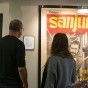 A man and a woman look at framed, vintage film posters by legendary filmmakers Akira Kurosawa and Sergio Leone.