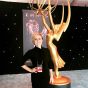 Jordyn Palos standing by a tall golden Emmy statue at the Emmy awards.