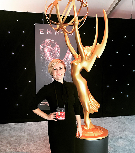 Jordyn Palos standing by a tall golden Emmy statue at the Emmy awards.