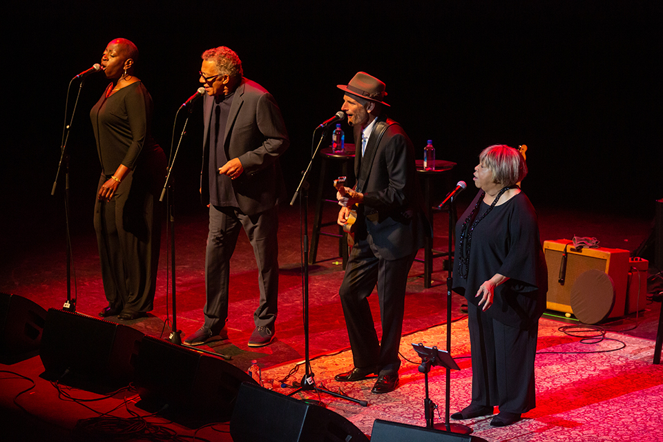Mavis Staples and her ensemble stand at microphones on The Soraya stage.