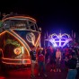 Students taking photos in front of a VW bus with neon lights.