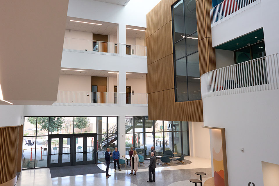 Wide shot of Maple Hall atrium, from upstairs, looking down on CSUN President Erika D. Beck and other campus leaders standing in the lobby.