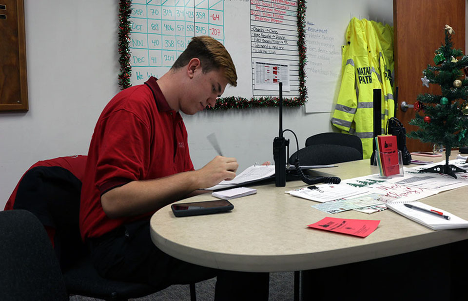 Matador Patrol community service officer Gabriel Gottfried, a mechanical engineering major, sits at a table at CSUN Department of Police Services, filling out a log sheet before the start of his safety escort shift.