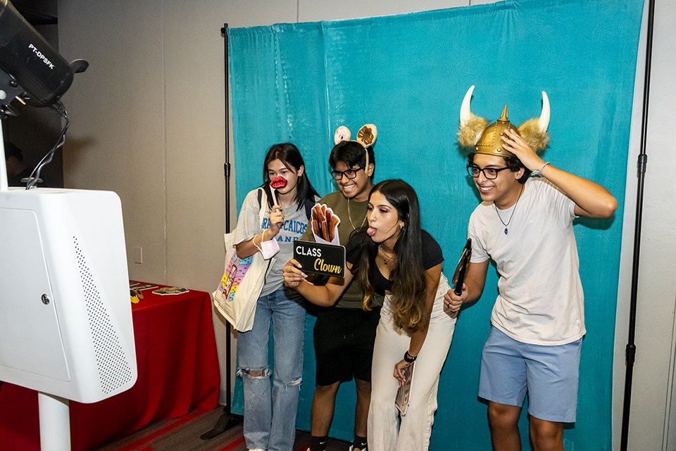 Four students pose at the photo booth with various props.