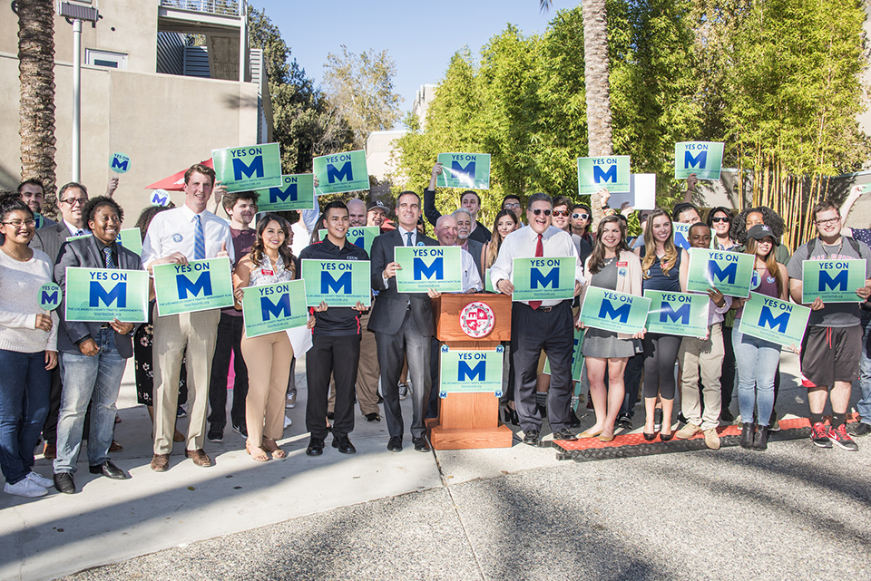 Large group poses with Measure M signs