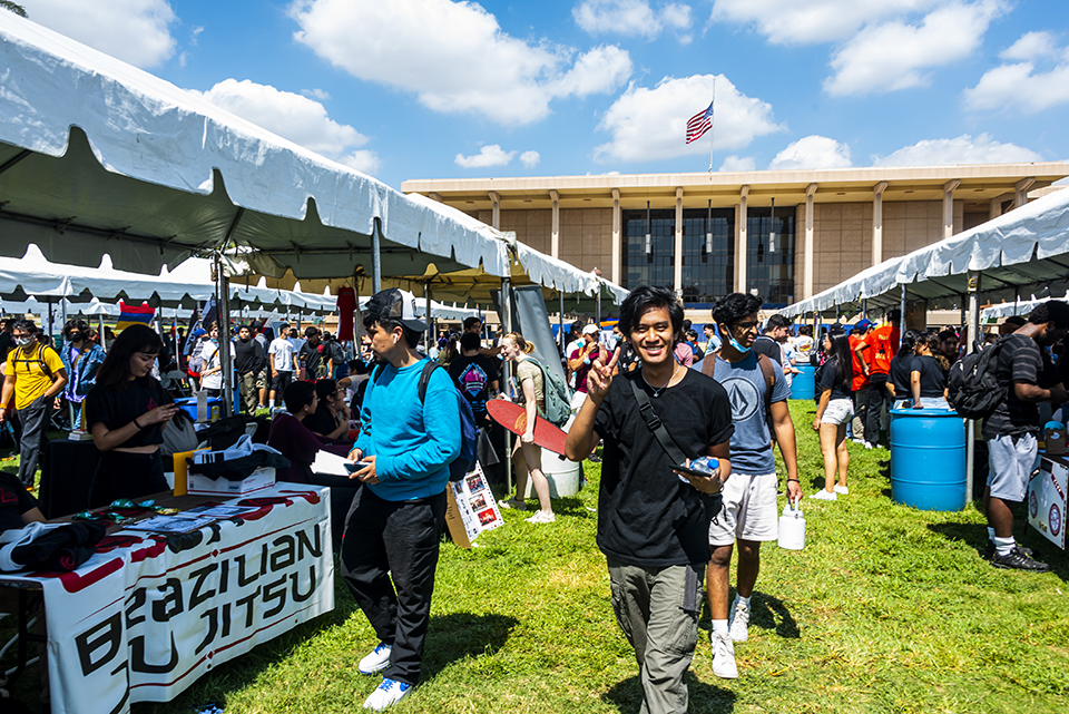 Students stand on the grass in the Sierra Quad with booths on both sides. The jiu jitsu booth is off to the left.