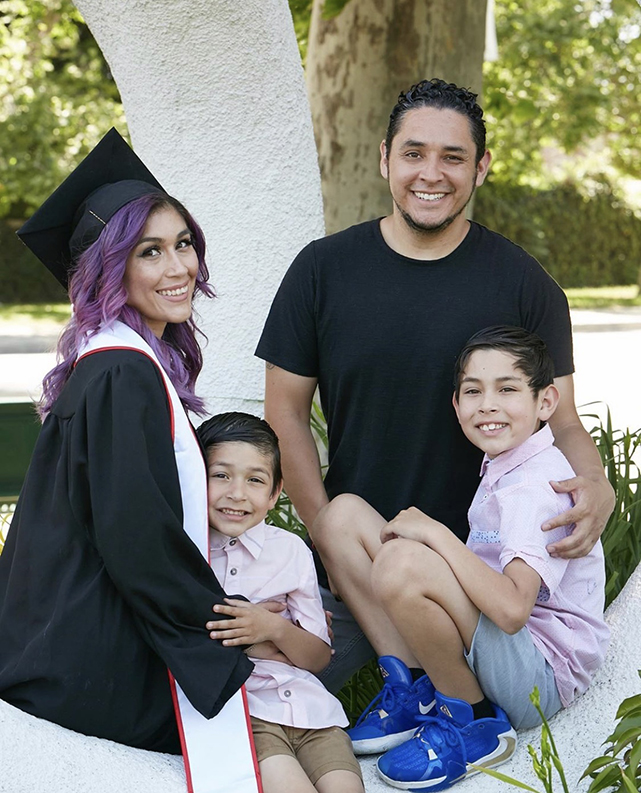 A CSUN graduate in her cap and gown poses with a man and two children.