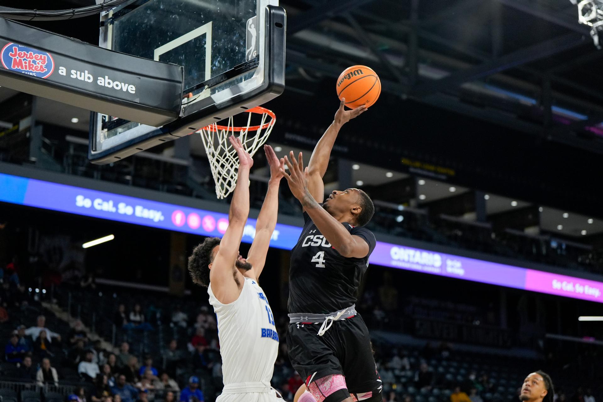 Men's basketball forward Keonte Jones skies over a UCSB player at the basket.