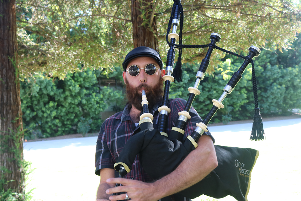 Miles Sweet holds the bagpipes and plays.