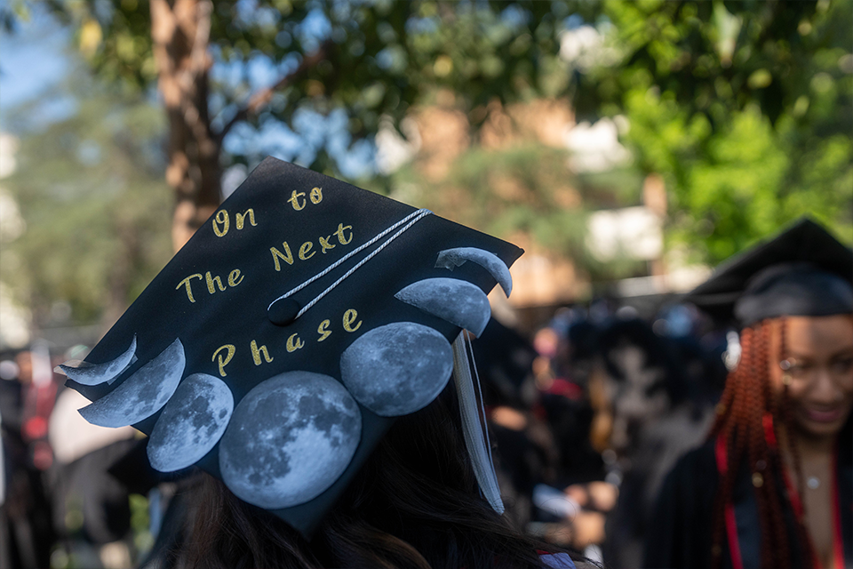 Mortarboard ringed with photos of the different moon phases, it says 