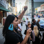 Noemi Tungüi raises a fist in the air as she stands on a street in Los Angeles.