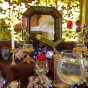 A traditional Persian New Year table set with a mirror in the center surrounded by white and red candles, colorful candies, fruit, pink flowers and goldfish.