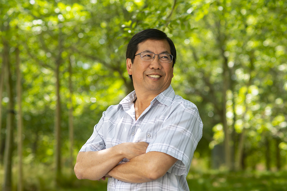 CSUN alumnus Jeff Okabayashi posing for a photo in front of trees.