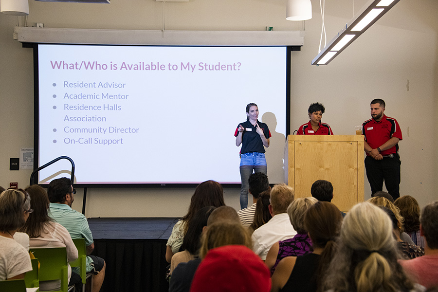 Three staff members stand on stage as they give an informative presentation on resources accessible to CSUN students.