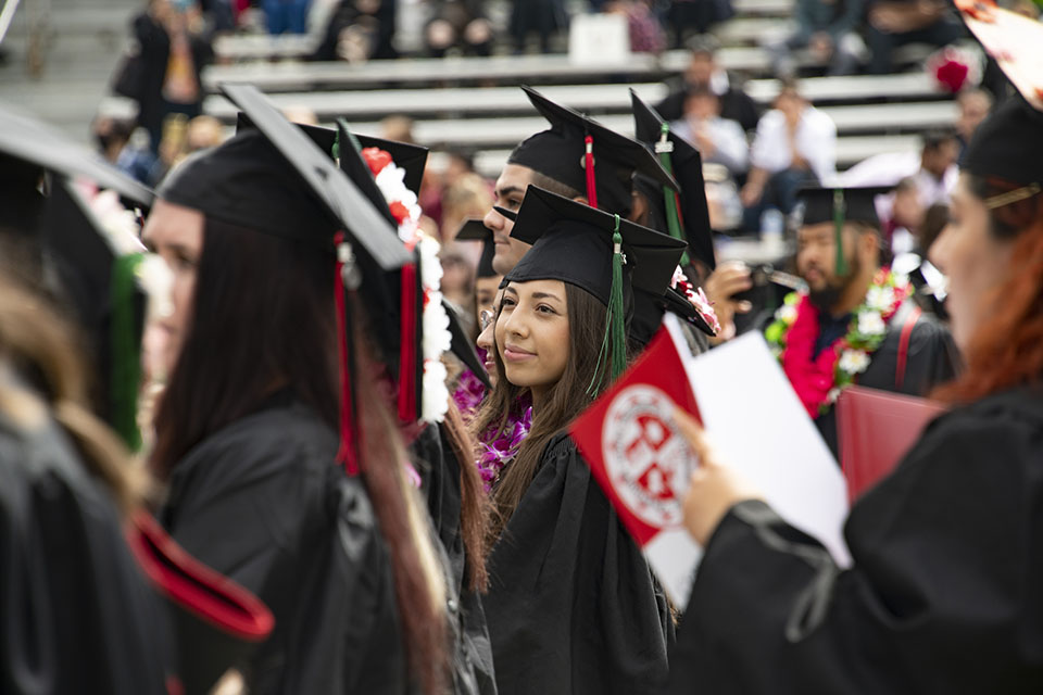 A crowd of CSUN graduates in caps and gowns looks toward the stage during Commencement ceremony.
