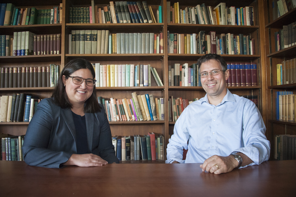 Chicana/o Studies professor Melisa Galván (left) and linguistics professor David Medeiros pose for a photo at a table.