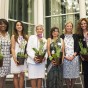 The women pose for the photo holding plants