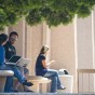 Student sits in front of University Library using her phone.