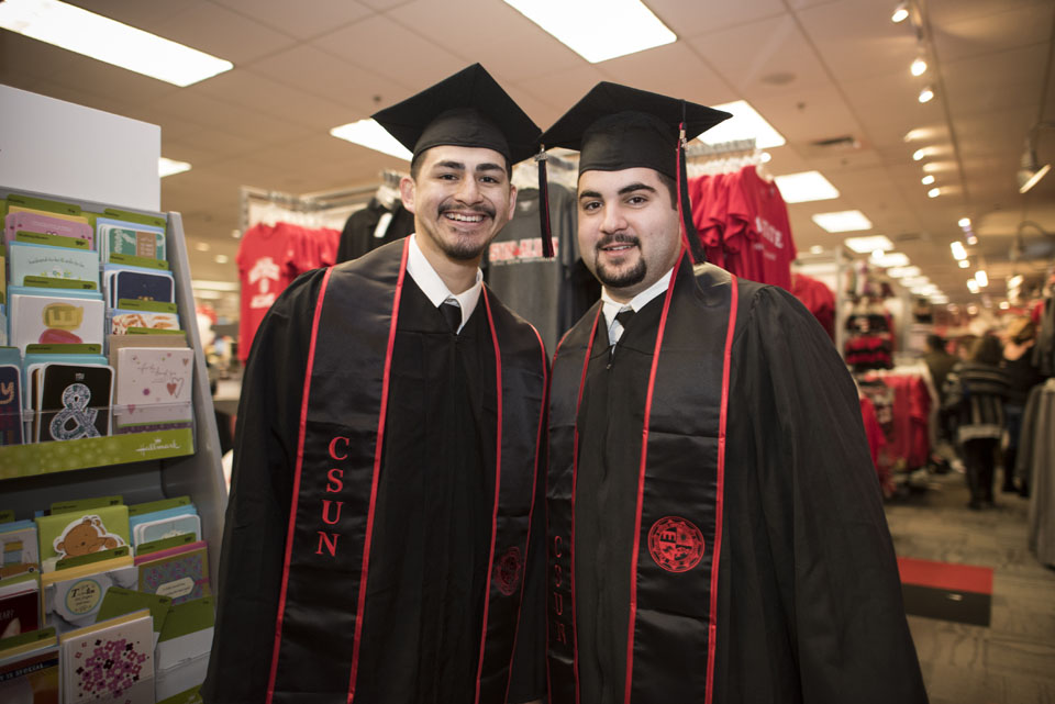 Two male students posing in cap and gown.