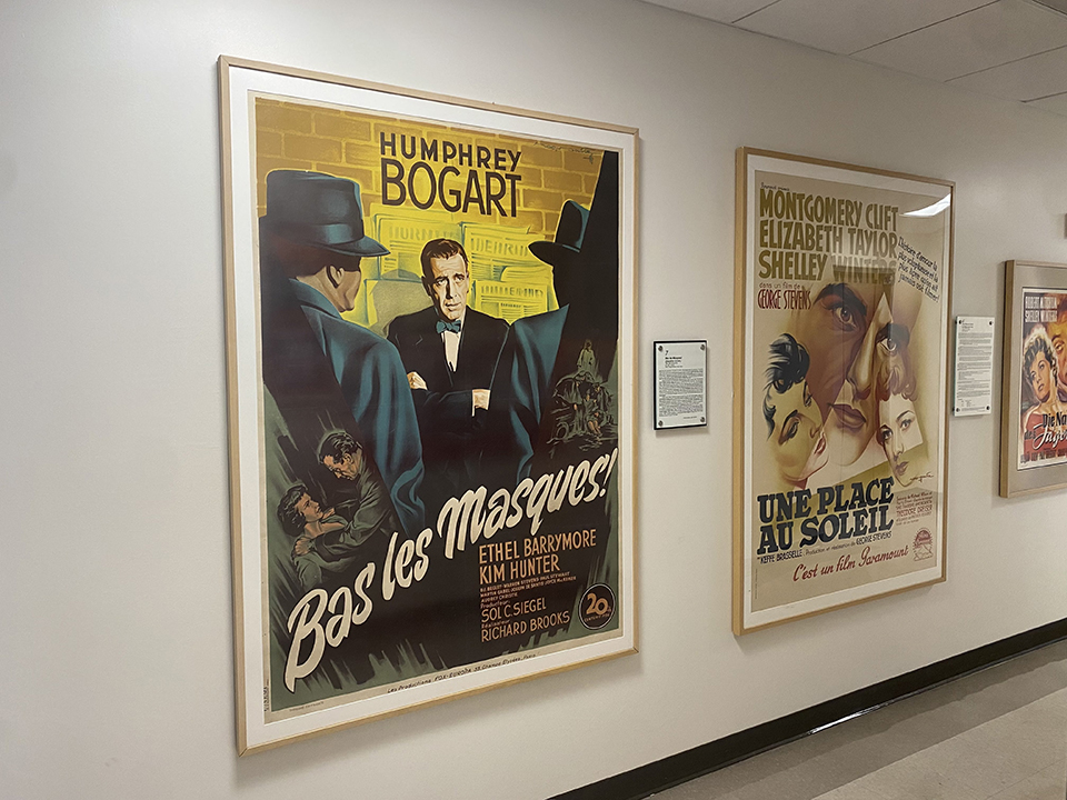 An image captured of two movie posters. One is for 'Bas les Masques,' a Humphrey Bogart Film and one is a poster for 'Une Place Au Soleil,' an Elizabeth Taylor film. 
