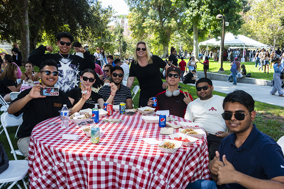 President Erika D. Beck stands behind picnic table with seated and standing students.