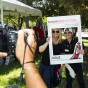 Hand holding camera in foreground, with CSUN President Erika D. Beck and student posing in a cardboard frame in background.