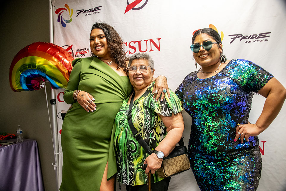 A family, decked out in green dresses and sequins, poses at the photo booth at the CSUN Pride Center gala.