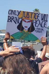A protester's sign reads, "Only justice will bring peace," quoted from the animated series, "Avatar: The Last Airbender."
