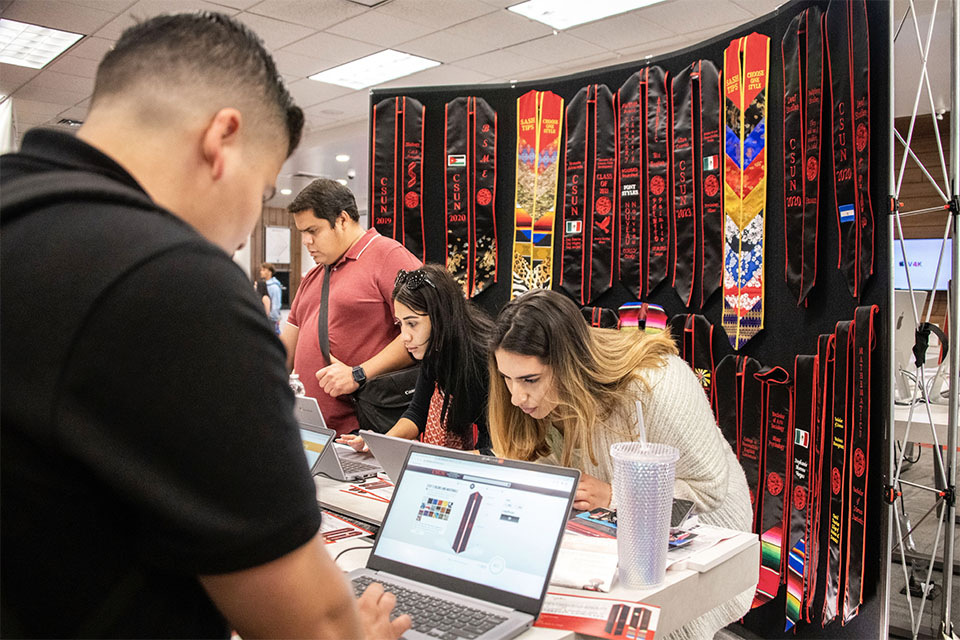 Students use computers set up by PrideSash to customize their sashes for graduation.