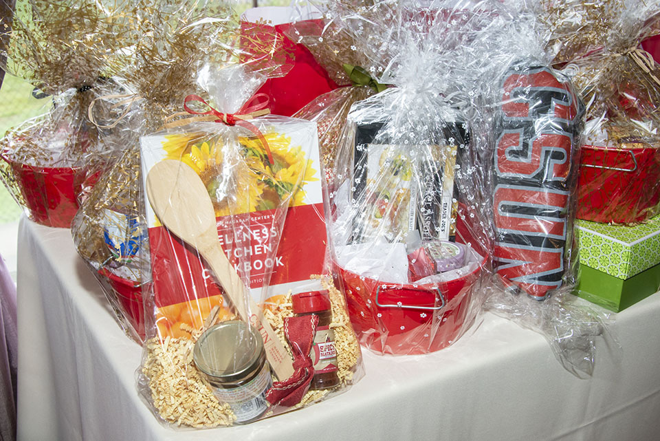A table with wrapped baskets, including prizes, CSUN cookbooks, T-shirts and other swag.