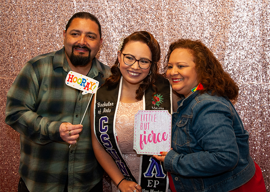 A student smiles for a photo at the photo booth with her parents at the Rainbow Graduation Celebration on May 17.