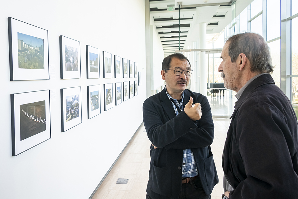 Ringo Chiu and Ed Alfano stand in front of a gallery of photos.