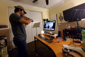 Violinist Ryan Porchas records his part in the symphony orchestra in his home studio.