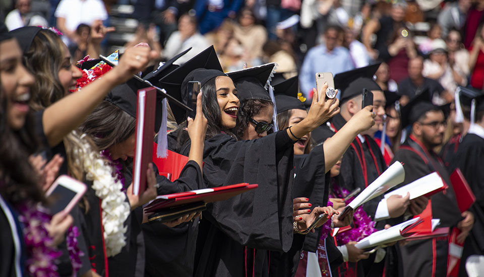 College graduates take pictures of themselves with their cellphones during CSUN 2019 commencement ceremony.