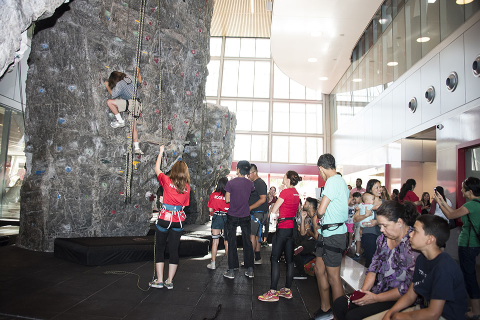 Attendees climb the 46-foot rock wall at the entrance of the Student Recreational Center.