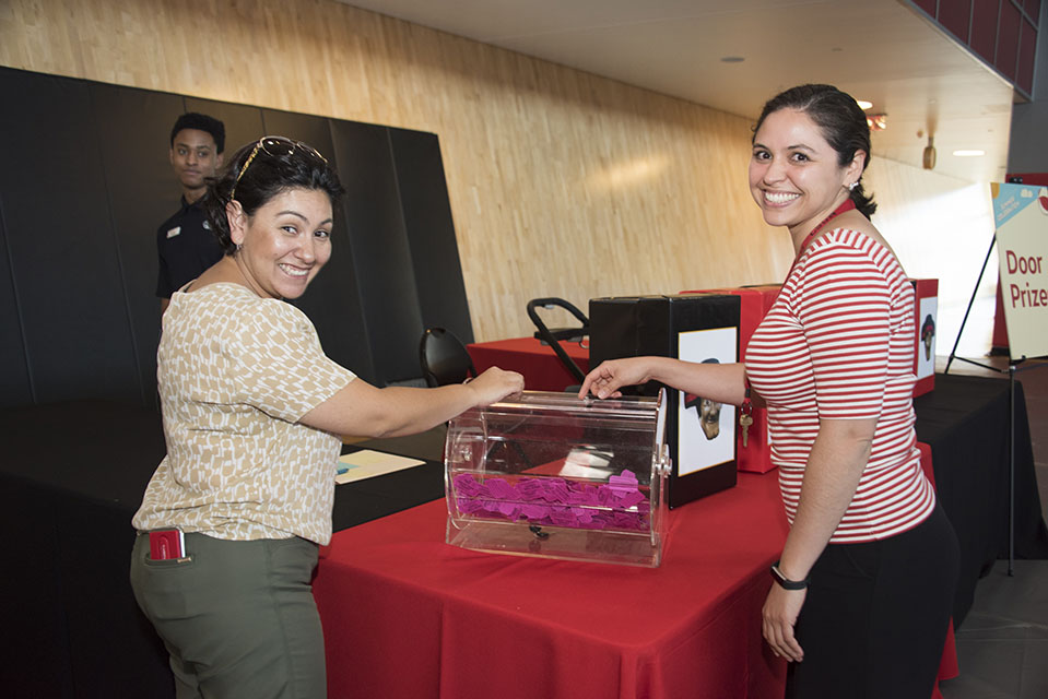 Two participants test out their luck and eagerly place a raffle ticket in a drawing box.