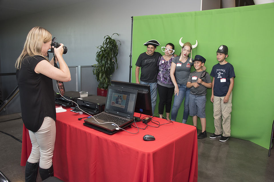 Attendees pose in front of a green screen as a photographer takes their photograph in the photo booth.