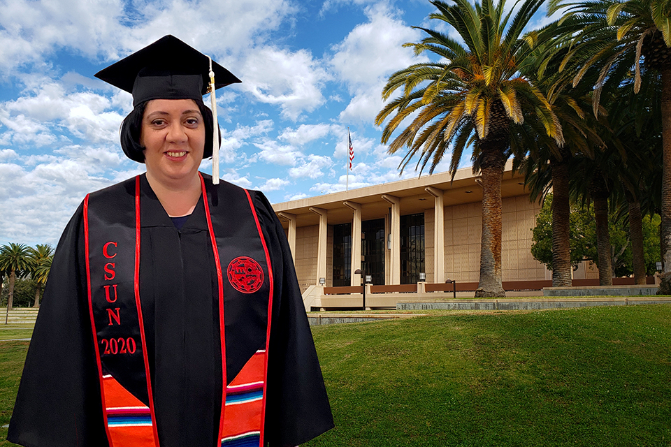 A female CSUN student poses in graduation cap and gown in front of a virtual CSUN Library background.