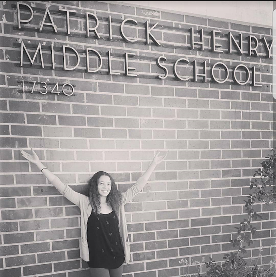 Dorothy posing for a photo with her hands above her in front of Patrick Henry Middle School wall sign.