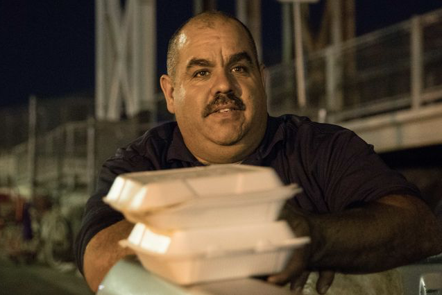 Manny Flores grabs plates of food to distribute to the homeless.