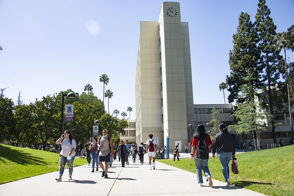 Students walk along the walkway next to the Sierra Hall Tower.