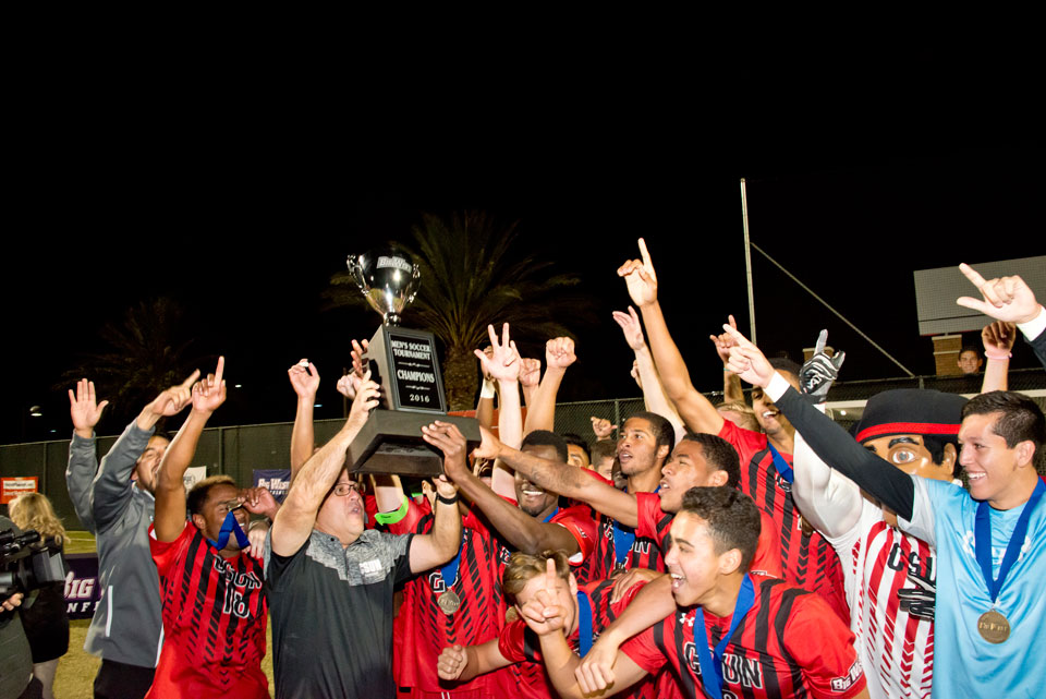 CSUN Men's soccer team raises the cup overhead.