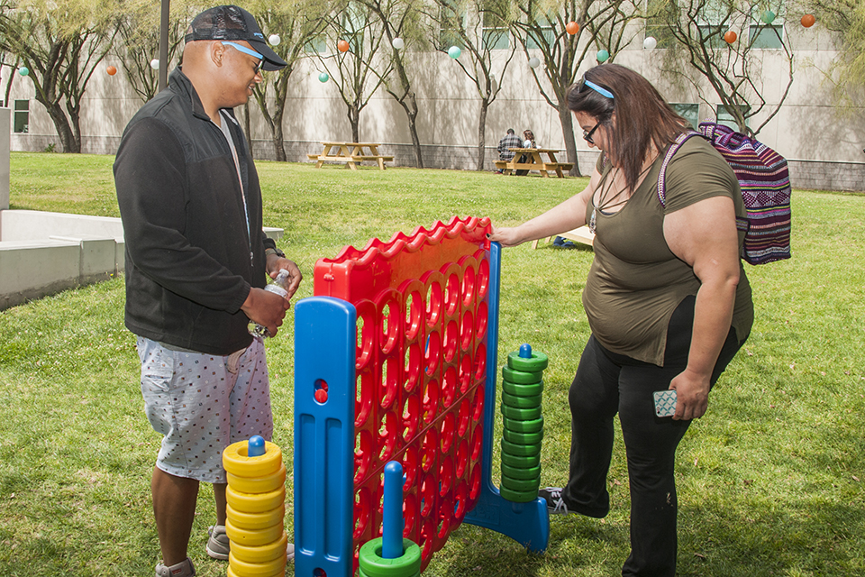 Two people playing oversized Connect Four at Sol Fest.