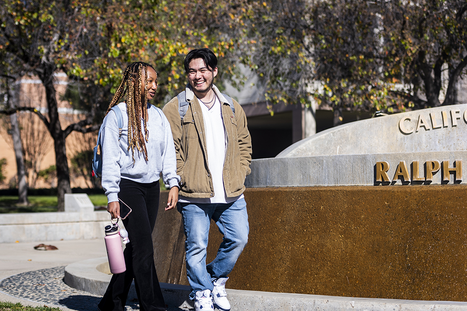 Two students walk together by the Ralph Prator fountain.