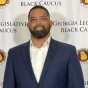 Steven Parker '94 (Political Science) stands in front of a step-and-repeat backdrop for the Georgia Legislative Black Caucus.