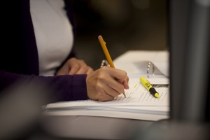 Close up of a person's hand holding a pencil and writing in a notebook