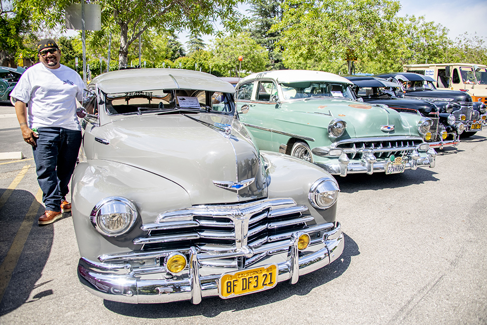 Shiny cars from the 1940's are parked in a line.