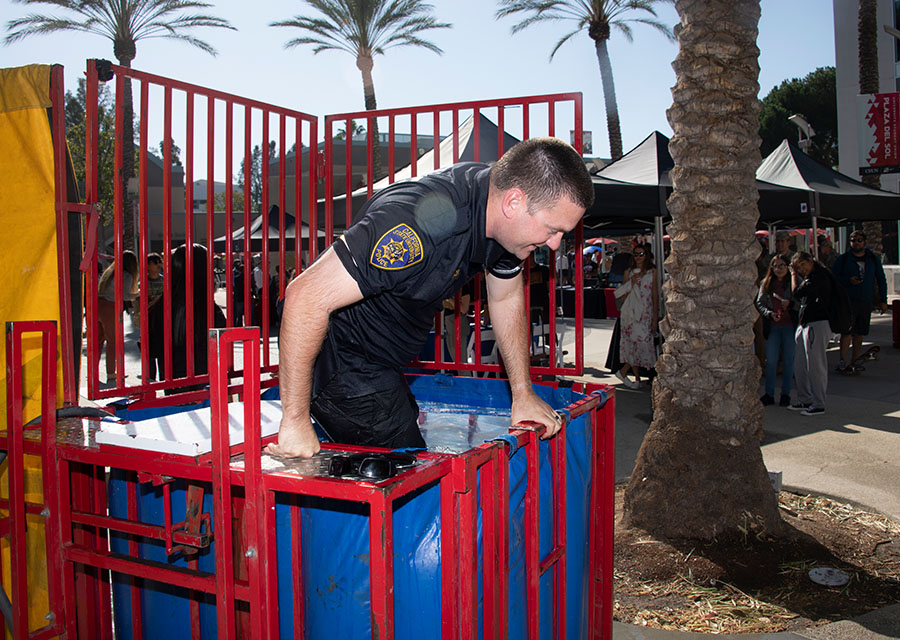 A member of the CSUN Department of Police Services climes out of the dunk tank after being dropped in the water.