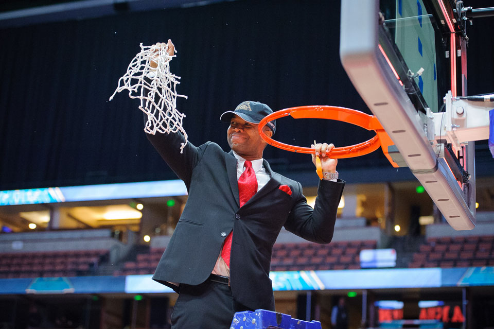 Coach Jason Flowers holds up net after it's been cut down.